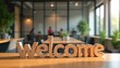 © Viktor - Wooden letters spell welcome on office table. Blurred background shows modern workspace with people. New employee greeting, onboarding, team integration.