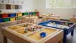 © Varos - An interior shot of a brightly lit preschool classroom featuring sensory activity tables filled with pasta, pom poms, sand, and water with toy ducks.
