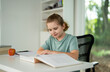 © Volodymyr - Kid reading book at home. Kid book studying. Child opening book indoors. Kid earning with books. Boy focused on textbook lesson. Clever teen reading storybook. Kid studying book at desk.