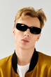 © LIGHTFIELD STUDIOS - Stylish young man with sunglasses showcases modern fashion trends indoors