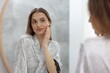 © New Africa - Beautiful young woman looking at herself in mirror indoors, selective focus