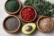 © whitestorm - A vibrant overhead view of healthy superfoods including spirulina, goji berries, chia seeds, quinoa, and avocado.