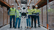 © ihorvsn - Warehouse staff standing proudly with humanoid robot in storage aisle. Wearing protective gear. Collaboration between humans and AI in logistics environment. Modern distribution center.