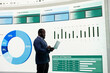 © DC Studio - Businessman compiling investment portfolio performance report using laptop device. African american man using notebook to prepare financial data pie charts slide deck for company shareholders