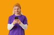 © Pixel-Shot - Young blonde man in hat using mobile phone on yellow background