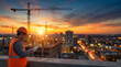 © Vera D - Civil engineer in hard hat and safety vest using digital tablet at construction site during sunset