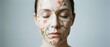 © Yuliia - Young woman with closed eyes and delicate floral face paint featuring botanical elements for beauty and artistic makeup concepts.