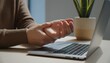 © dang - A close-up shot of a person sitting at a desk with a laptop, holding their hand due to wrist pain, suggesting work-related repetitive strain injury or carpal tunnel syndrome.