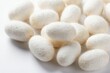 © Pete - White silkworm cocoons gathered in pile on clean surface. Natural silk production start. Insect larvae create silk fiber for fabric industry. Moth pupae stage.