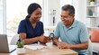 © Muchamad Musa - Nurse explains health results to a smiling older man using a digital device during an appointment at a modern medical office.