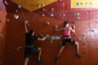 © New Africa - Athletic man and woman climbing wall in gym, back view
