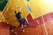 © New Africa - Athletic young man climbing wall in gym, back view. Space for text