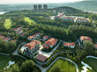 © zhu difeng - Aerial view of red-roofed villas adjacent to a lush golf course with surrounding greenery and distant hills