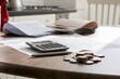 © Juan - Household budget documents with calculator and coins on kitchen table