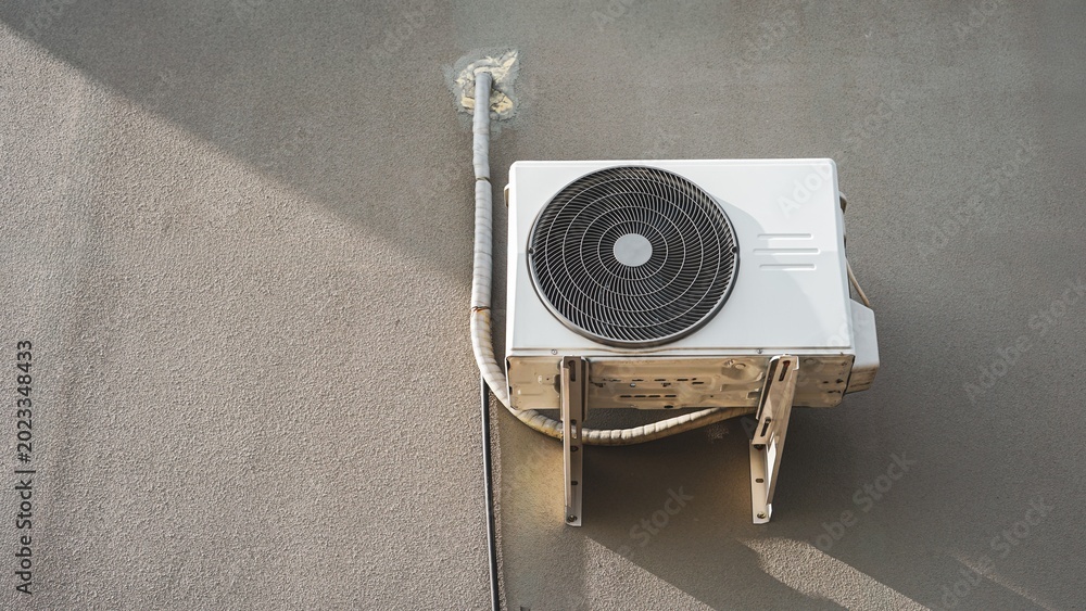 Outdoor air conditioner compressor unit mounted on concrete wall. の ...
