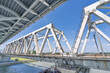 © Jin - White Steel Truss Railway Bridge Over River Repeating Geometric Structure Blue Sky Perspective