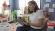 © Krakenimages.com - Woman writes on clipboard with pen amid colorful toys and cubbies in kindergarten building; focused observation.