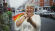© Krakenimages.com - Woman laughing and beckoning with finger while carrying orange and yellow shopping bags on a busy city street; joy carefree celebration.