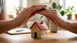 © Jimmie - Hands protecting miniature house, home insurance, security concept.