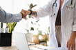 © Studio Marmellata - A doctor in a white coat shakes hands with a patient, symbolizing trust and a successful consultation in a modern medical office.
