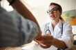 © Studio Marmellata - A doctor in a white coat and glasses consults with a patient, holding their arm gently.