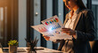 © RATUL HASAN - Professional businesswoman reviewing marketing infographic reports in modern office during sunset with warm golden hour light.