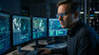 © REAL  - Soft focus blurred photo of Serious male software engineer working late at night on multiple computer screens showing lines of complex code in a dark high tech office environment