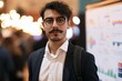 © Khawla - Confident Professional at Conference with Data Display. 20s hispanic man stands in front of a board with a lot of numbers on it. He is wearing a suit and glasses
