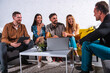 © alphaspirit - Friends talk and laugh while sitting in a cozy living room during a weekend gathering with a laptop on the table