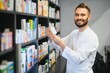 © Serhii - Pharmacist holding medicine bottle in front of pharmacy shelves