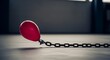 © Janfau - Red balloon tied to a heavy metal chain on a dark floor representing restraint