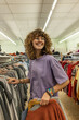 © Westend61 - Smiling teenage girl shopping secondhand clothing at a flea market