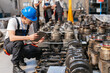 © Westend61 - Engineer kneeling in factory inspecting engine part with tablet