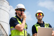 © DJ Creative Studio - Refinery Engineer Using Walkie Talkie During Petroleum Infrastructure Inspection At Petrochemical Energy Facility