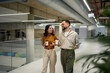 © Migma_Agency - Business colleagues walking, talking, and drinking coffee in office