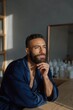 © Iryna - Bearded man pondering by window in bathroom interior