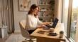 © For You Retouch - A smiling female freelancer in a white sweater sitting at her clean wooden desk and working on a laptop from home