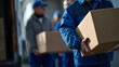 © rohit - Delivery crew in blue uniform unload cardboard packages from a truck, focusing on a front worker's hands, illustrating efficient, reliable shipping and logistics