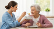 © SYATRI RAWU - Young female nurse or caregiver feeding healthy soup to a senior woman in a nursing home or at home setting, providing assistance and care