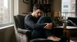 © Olinka N - A man is sitting in a chair with his legs curled up. He has a thoughtful look on his face. The room is bright and has bookshelves. Light comes from a window