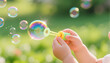 © Margarita - Baby blowing bubbles while playing outdoors in sunny garden