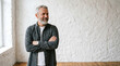 © Sumanta - portrait of a handsome young man. A man with graying hair and a beard, wearing a dark gray button-down shirt over a white t-shirt, standing with his arms crossed.