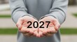 © Sheik - A person holding the year 2027 in their cupped hands illustration