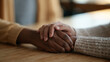 © forenna - Close detail of two hands clasped across a cafeteria table, one belonging to a teenage girl reporting workplace harassment to a trusted female manager, the single object of their interlocked grip co