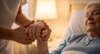 © improvee design - caregivers hands gently holding an elderly womans hands as she rests in a hospital bed, illuminated by warm bedside lamp light.
