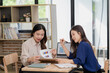 © MrAshi - Two Asian women work together, with reports, charts, and graphs piled on a desk along with a laptop containing accounting concepts.
