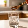 © SayedBin - Hand pouring chia seeds into a glass of water on a kitchen counter