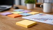© Thares2020 - A wooden desk surface is arranged with colorful sticky notes documents and a plant symbolizing creative business planning and success