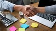 © Thares2020 - Professional hands engage in a successful business handshake over a laptop symbolizing collabo n and partnership in a creative workspace