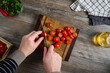 © SKfoto GE - A top view of a man cutting cherry tomatoes on a beautiful wooden board.